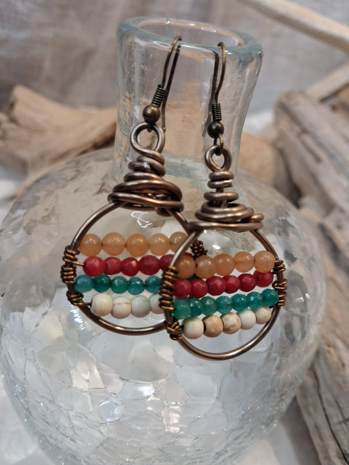 Amber, red, teal and white beaded boho hoop earrings with wire-wrapped metal frames, handmade by Melly