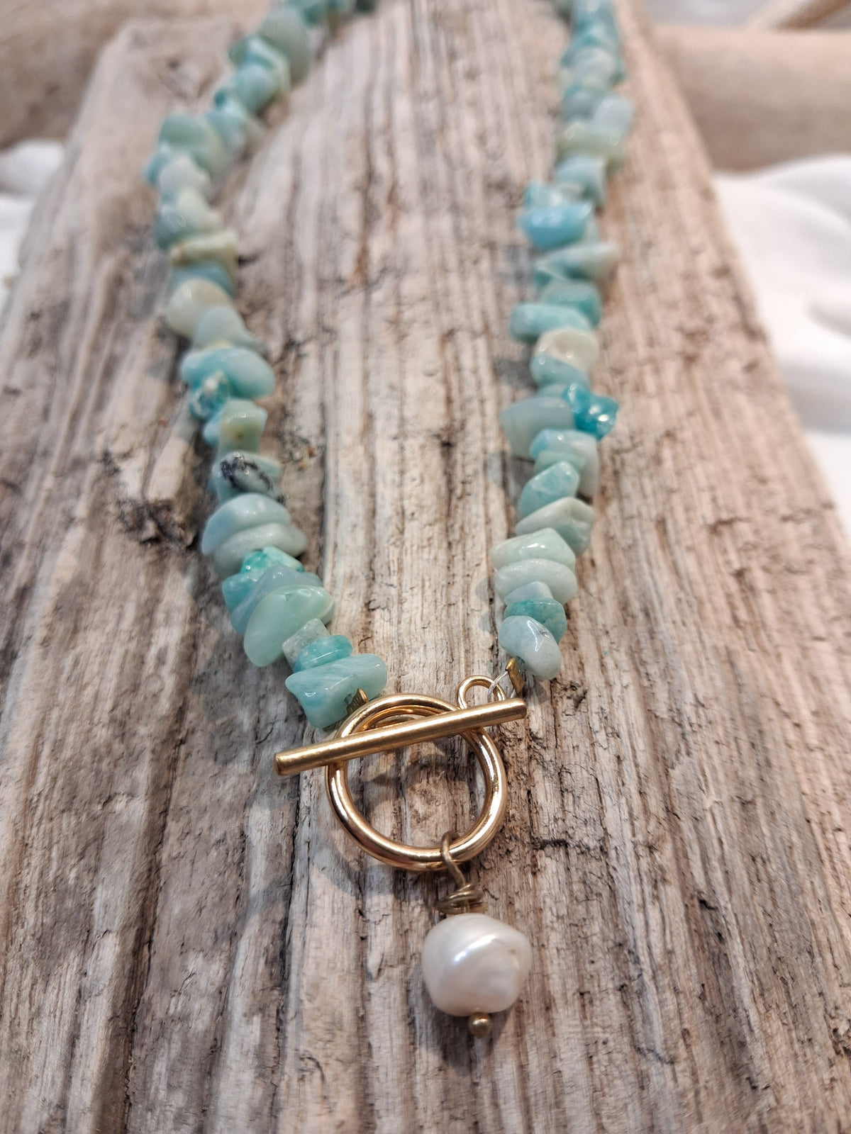 Light blue chipstone gemstone necklace featuring a gold toggle clasp and pearl charm, handmade by Melly