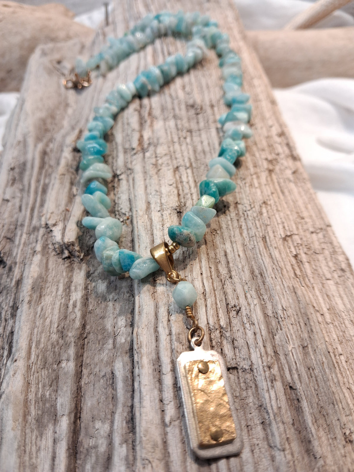Blue aquamarine beaded single strand necklace featuring natural stone chips and a metallic pendant, handmade by Melly