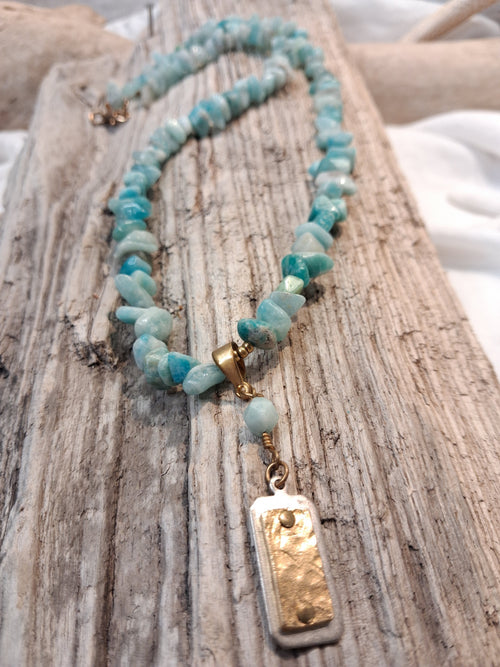 Blue aquamarine beaded single strand necklace featuring natural stone chips and a metallic pendant, handmade by Melly