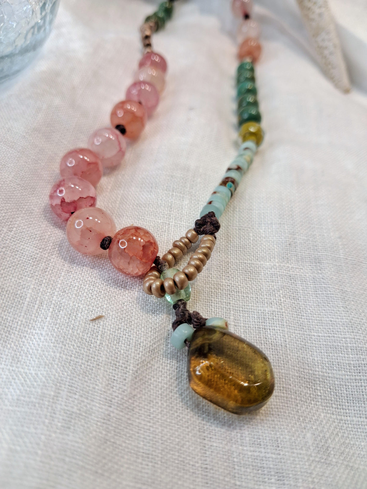 Pink and green gemstone beaded necklace featuring a brown amber pendant, handmade by Melly