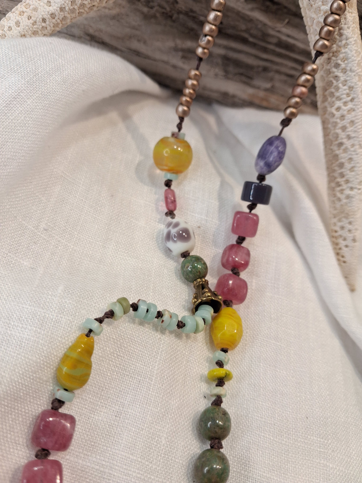 Multi-color beaded necklace featuring glass and stone beads on a dark cord, handmade by Melly