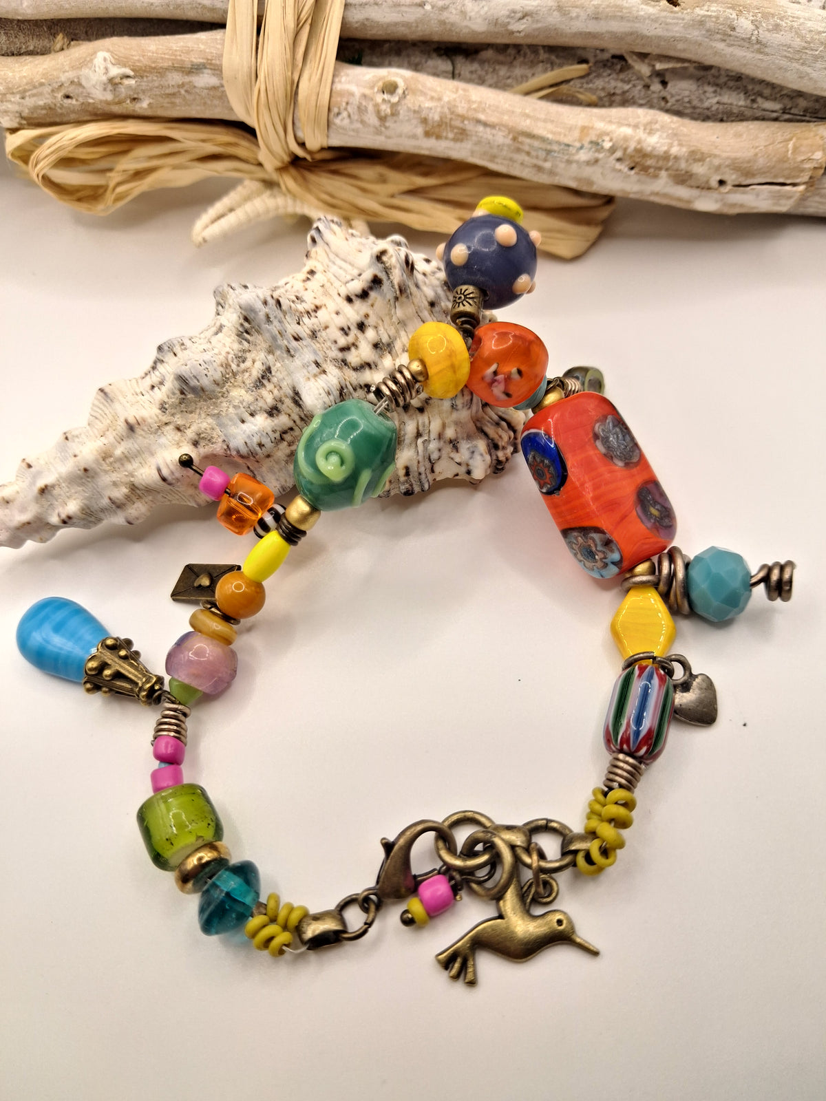 Multicolor beaded mocking bird charm bracelet featuring assorted glass beads and metal charms, handmade by Melly