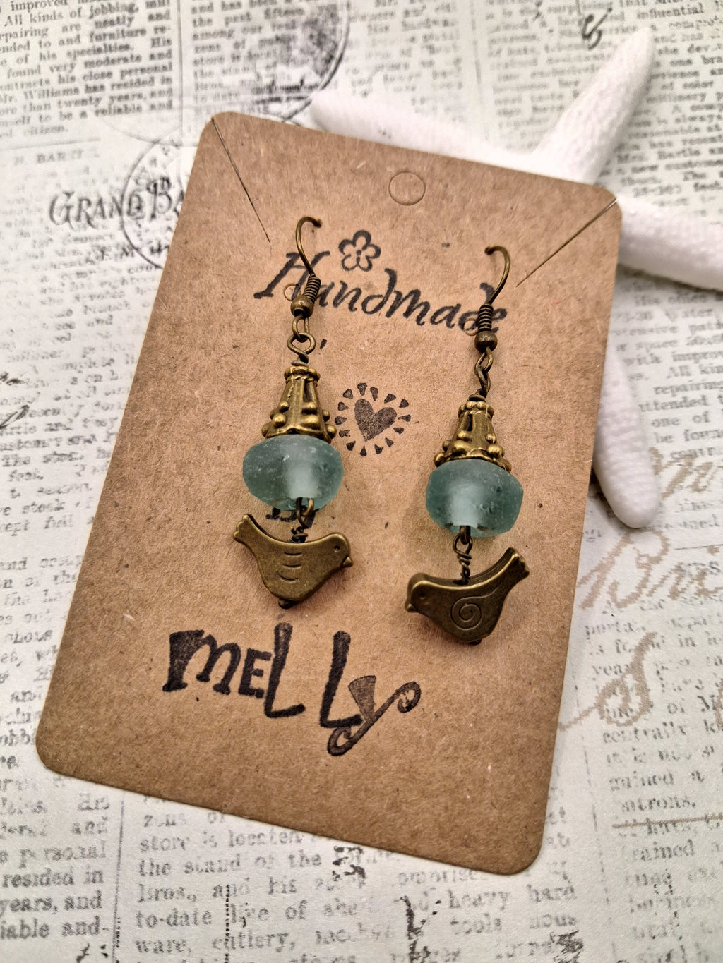 Teal glass beads and brass bird charms on dangle earrings, handmade by Melly