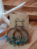 Turquoise and wire wrapped siesta hoop earrings displayed on a card, handmade by Melly