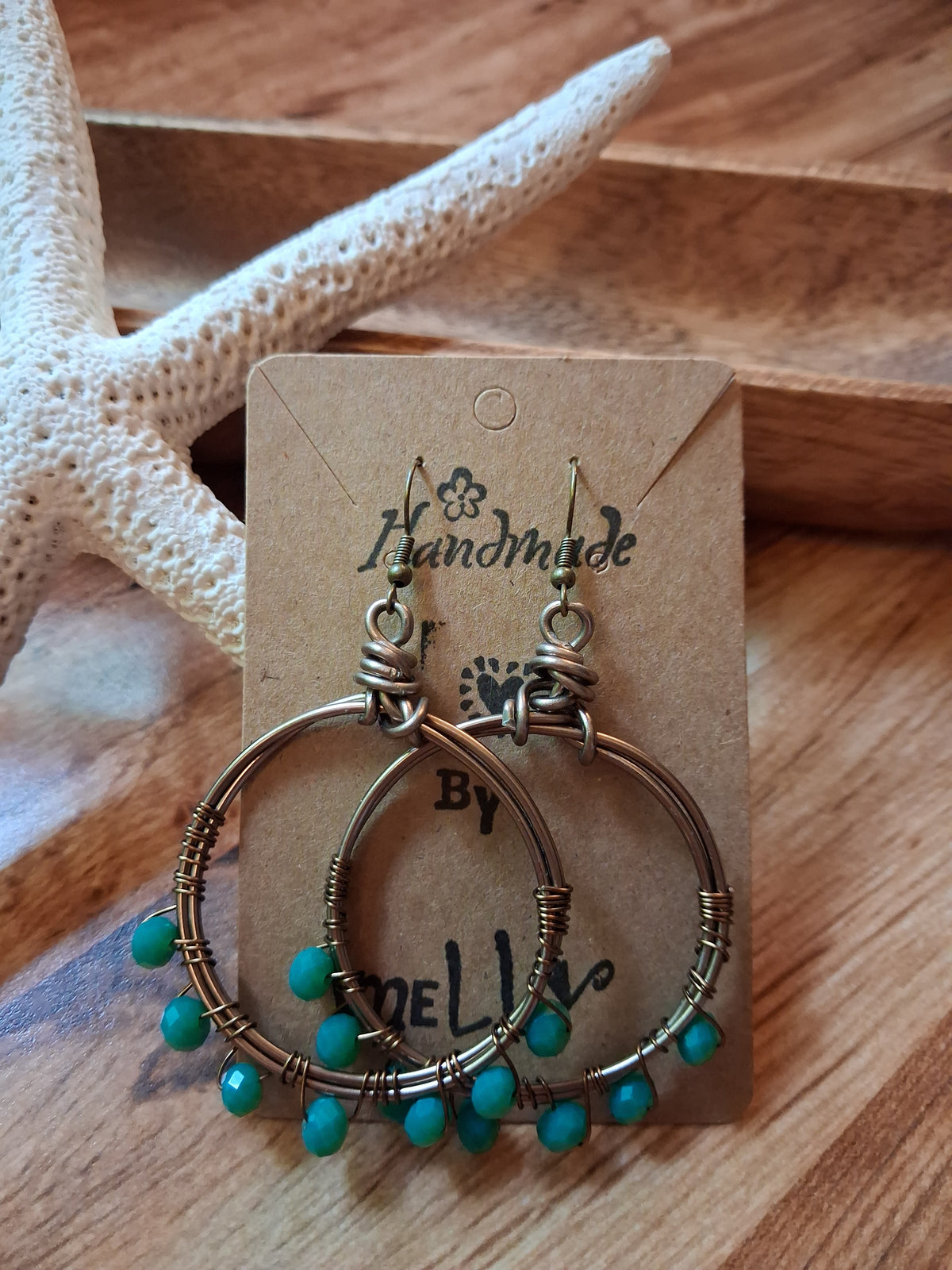 Turquoise and wire wrapped siesta hoop earrings displayed on a card, handmade by Melly
