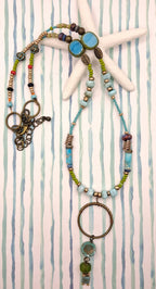Turquoise, teal, and olive beaded sea shore necklace featuring metal and glass components handmade by Melly
