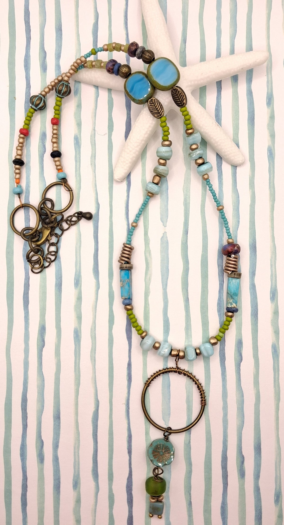 Turquoise, teal, and olive beaded sea shore necklace featuring metal and glass components handmade by Melly