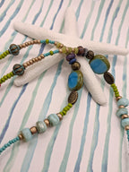 Blue and green beaded necklace featuring glass beads and bronze metal accents, handmade by Melly